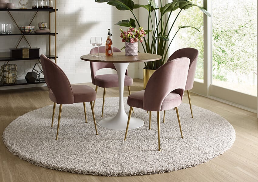 A round area rug beneath a round table surrounded by chairs