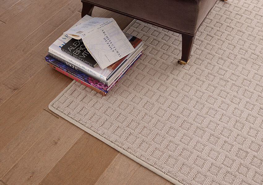 A large square area rug on light-colored hardwood flooring