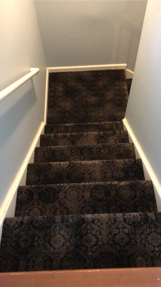 A dark pattern carpet leads down the stairs
